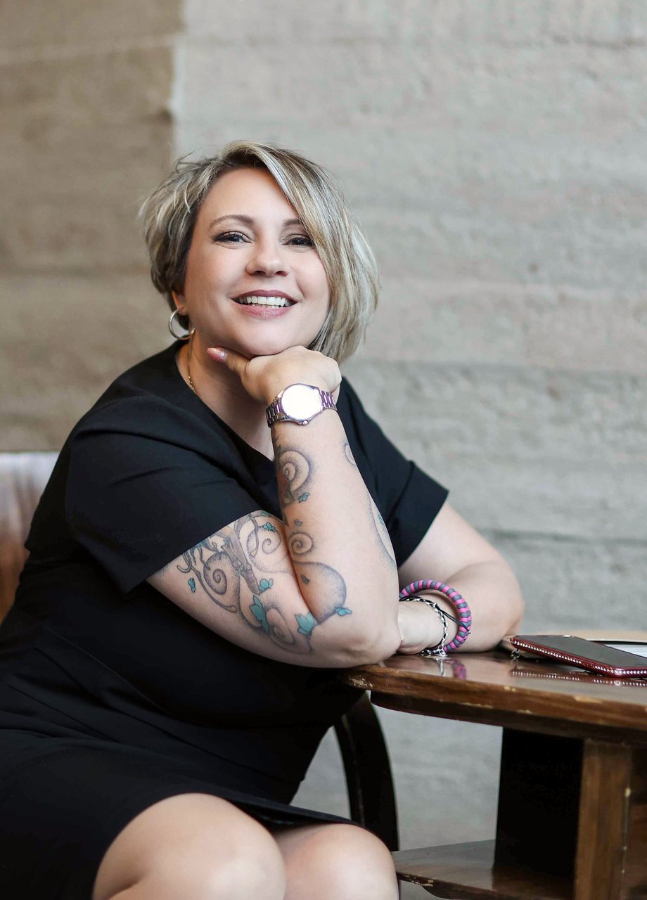 angelika-stempfle-wer-ich-bin Angelika Stempfle lacht im Café, das Kinn auf die Hand gestützt